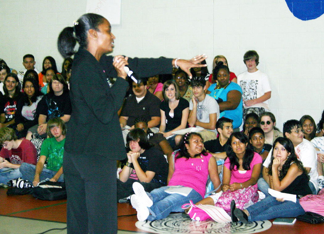 Click to enlarge,  Tania Brewington, teacher assistant, welcomes students to Lee Early College at an assembly Wednesday, the first day of classes. The college, located on Central Carolina Community College's Lee County Campus, is a collaboration between the college and Lee County Schools. Students attend for five years and earn both a high school diploma and an associate degree at no cost to them. 