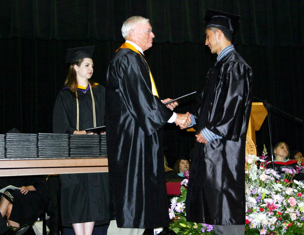 Click to enlarge,  Gerzain Santana (right), of Sanford, received his Associate in Arts-University Transfer degree from Bobby Powell, chairman of the Central Carolina Community College Board of Trustees, during the college&#8217;s Summer Commencement exercises Friday in the Dennis A. Wicker Civic Center. During the summer, 89 students completed degrees, 102 earned diplomas, and 84, certificates. Teddy Byrd, chairman of the Harnett County Board of Commissioners delivered the commencement address. 