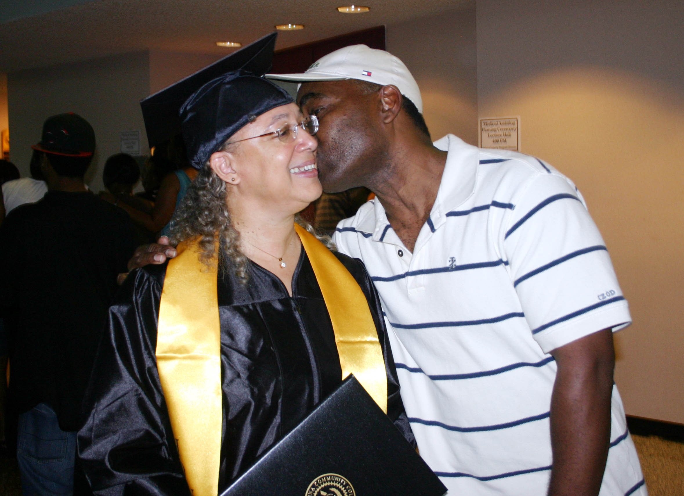 Click to enlarge,  Dorothy Combs Hunter, of Sanford, receives a congratulatory kiss from her husband, Joseph, after receiving an Associate in Applied Science in Business Administration degree during Central Carolina Community College&#8217;s Summer Commencement exercises Friday in the Dennis A. Wicker Civic Center. During the summer, 89 students completed degrees, 102 earned diplomas, and 84, certificates. Teddy Byrd, chairman of the Harnett County Board of Commissioners delivered the commencement address.  