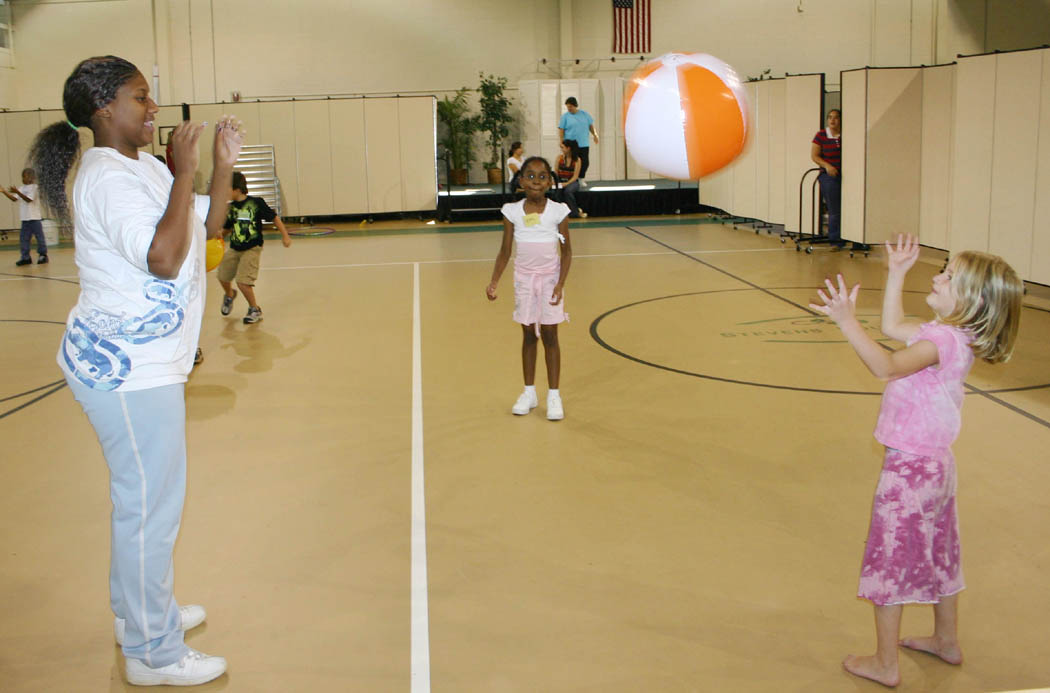 Click to enlarge,  Shatara Farrow (left), of Sanford, smiles as she tosses a ball to Savannah Flowers, as Zoey Davis (center) waits her turn during the Stevens Center&#8217;s Party, Paint and Playtime summer camp, held during June and July. Farrow is enrolled in Central Carolina Community College&#8217;s early childhood education program. Her &#8216;Child, Family, and Community&#8217; class collaborated with nursing students from UNC-Chapel Hill to staff and plan activities for the Center&#8217;s summer camp for 2-to-4-year-olds and the Kids Can Connect camp for 5-to-8-year-olds. Both camps included children with and without disabilities. The nursing students gained experience working in the community and the CCCC students applied what they had learned in class about working with young children with and without disabilities, individually and in groups. 