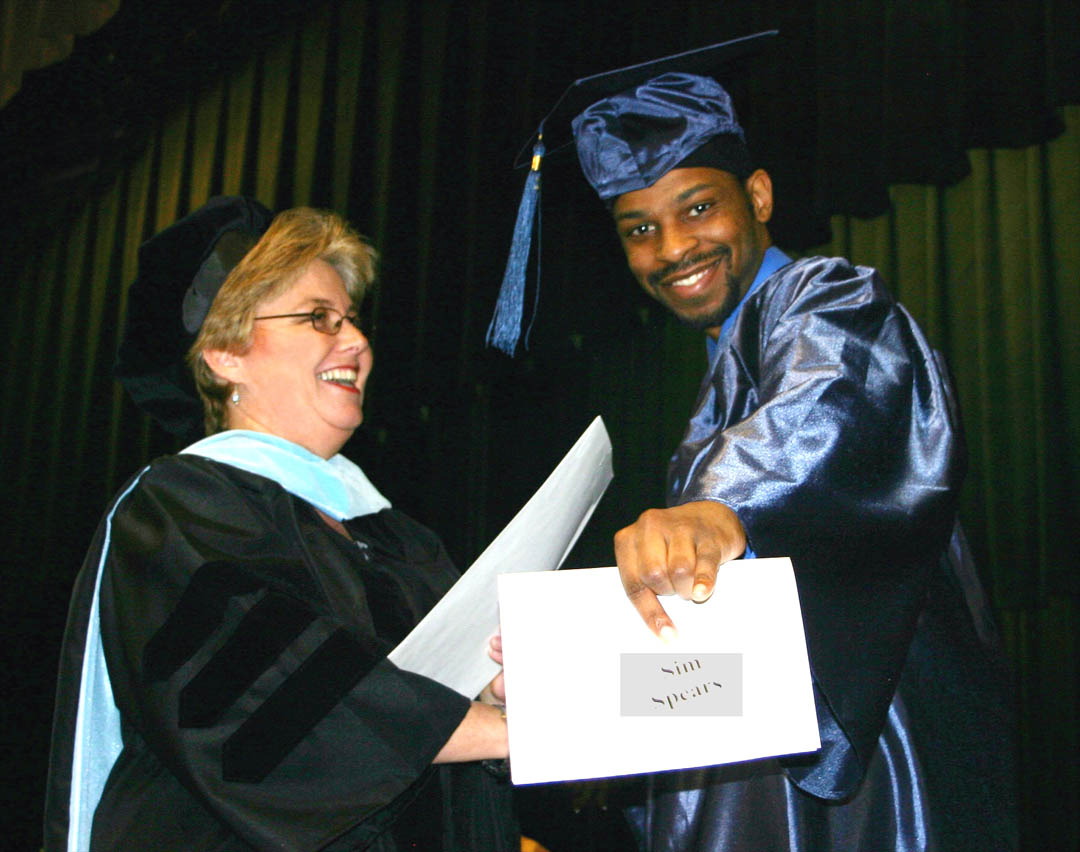 Click to enlarge,  Sim Spears, of Lee County, is all smiles as he accepts the W.B. Wicker Scholarship from Dr. Lisa Chapman, Central Carolina Community College&#8217;s vice president of Instruction. The presentation took place during graduation exercises for the college&#8217;s Continuing Education high school completion programs. During the exercises, held Jan. 29 in the Dennis A. Wicker Civic Center, fall semester graduates were awarded their high school diplomas or GED certificates. More than 60 adults, including Spears, earned diplomas and more than 200, GEDs during the fall semester.  