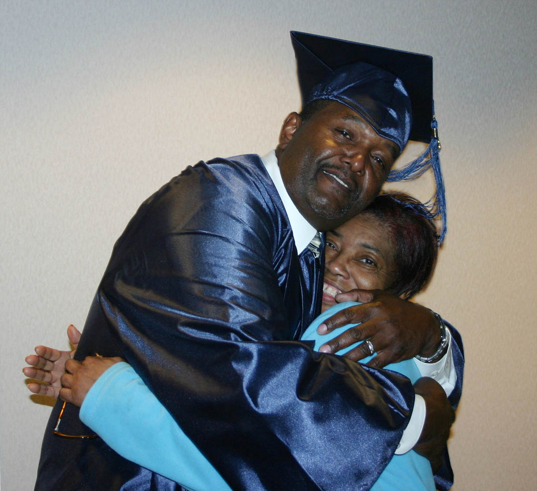 Click to enlarge,  Glenda Goldsby (right), an Adult High School instructor at Central Carolina Community College&#8217;s Jonesboro Center, gets a thank-you bear hug from graduating student John Taylor, of Chatham County, at the college&#8217;s high school completion programs commencement exercises Jan. 29 in the Dennis A. Wicker Civic Center. Taylor was one of more than 60 adults who earned their high school diplomas at the college during the fall semester. More than 200 students earned General Educational Development certificates.  