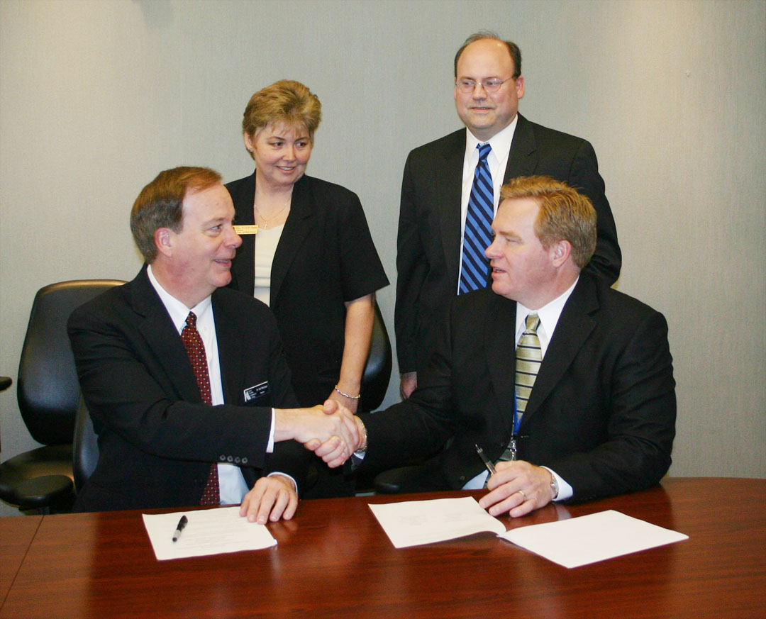Click to enlarge,  Dr. Bud Marchant (seated, left), president of Central Carolina Community College, and Dr. Jeffrey Moss, Superintendent of Lee County Schools, shake hands over an agreement to start E-Lee College Academy, an initiative that will broadcast selected curriculum courses at Central Carolina to students in computer labs at Southern Lee and Lee County high schools. Witnessing the signing are (standing, from left) Dr. Lisa Chapman, the college&#8217;s Vice President of Instruction, and Andy Bryan, the school district&#8217;s Assistant Superintendent for Curriculum and Instruction. The Academy offers college-bound juniors and seniors up to 45 semester credit hours of General Education Core courses. These are part of the college&#8217;s Associate in Arts degree program, and will transfer to colleges and universities in the University of North Carolina System. The students will also receive high school credit for them toward their diploma. The N.C. Department of Public Instruction&#8217;s Learn and Earn Initiative will pay all tuition and textbook costs. Contact school guidance counselors for more information. April 1 is the deadline to enroll. 