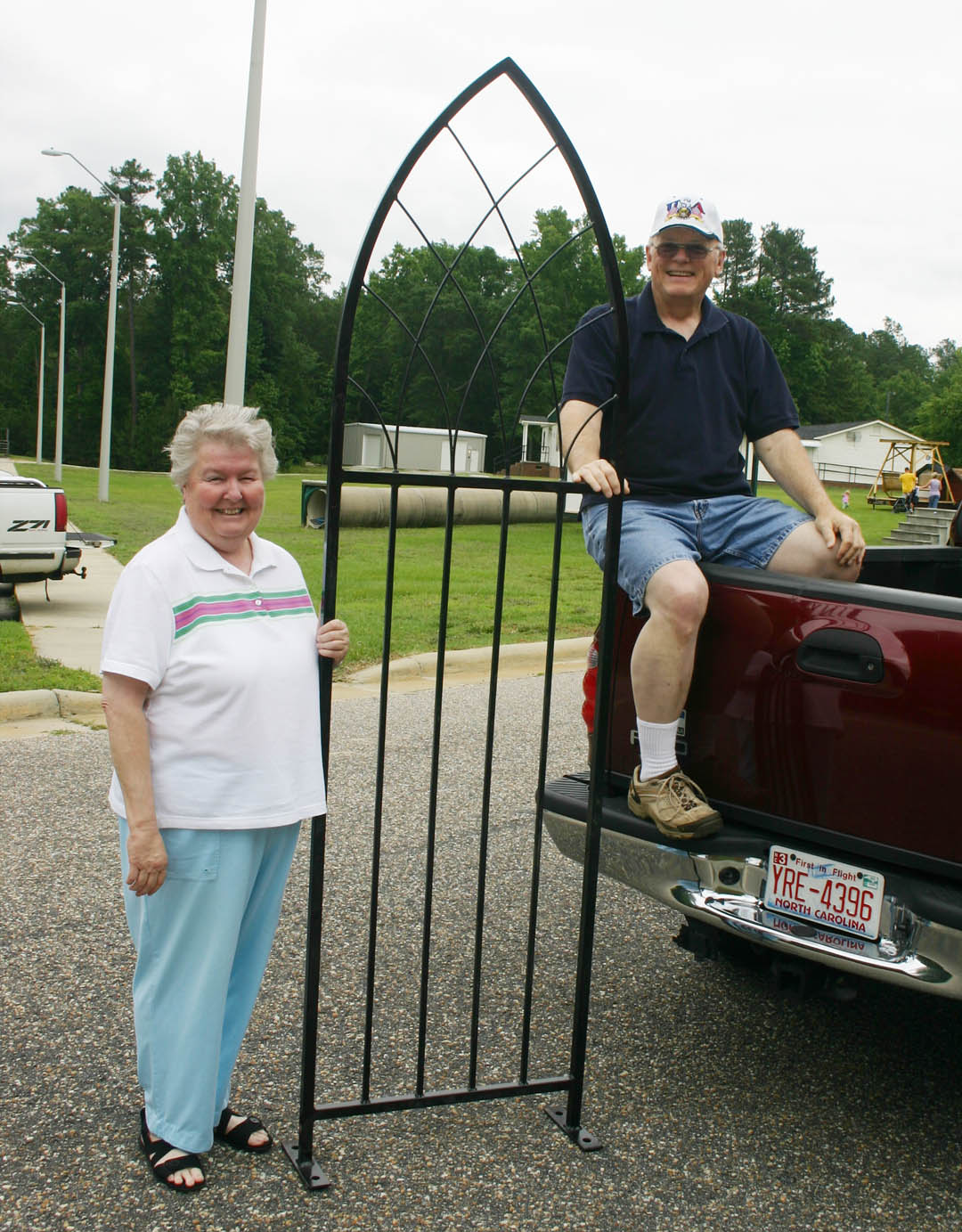 Click to enlarge,  Betty (left) and Marty Walker, of Carolina Trace, smile as they load a metal cathedral arch for which they were high bidders at the Central Carolina Community College Foundation&#8217;s Furniture Auction June 6. The auction, at the college&#8217;s Harnett County Campus in Lillington, attracted more than 100 people. A variety of wood and metal furnishings were auctioned for a total of more than $19,000. Student inmates of the college&#8217;s carpentry and welding programs in the Harnett Correctional Institution made all the pieces. Proceeds from the annual auction go into an endowment that provides scholarships for Central Carolina students from Harnett County. 
