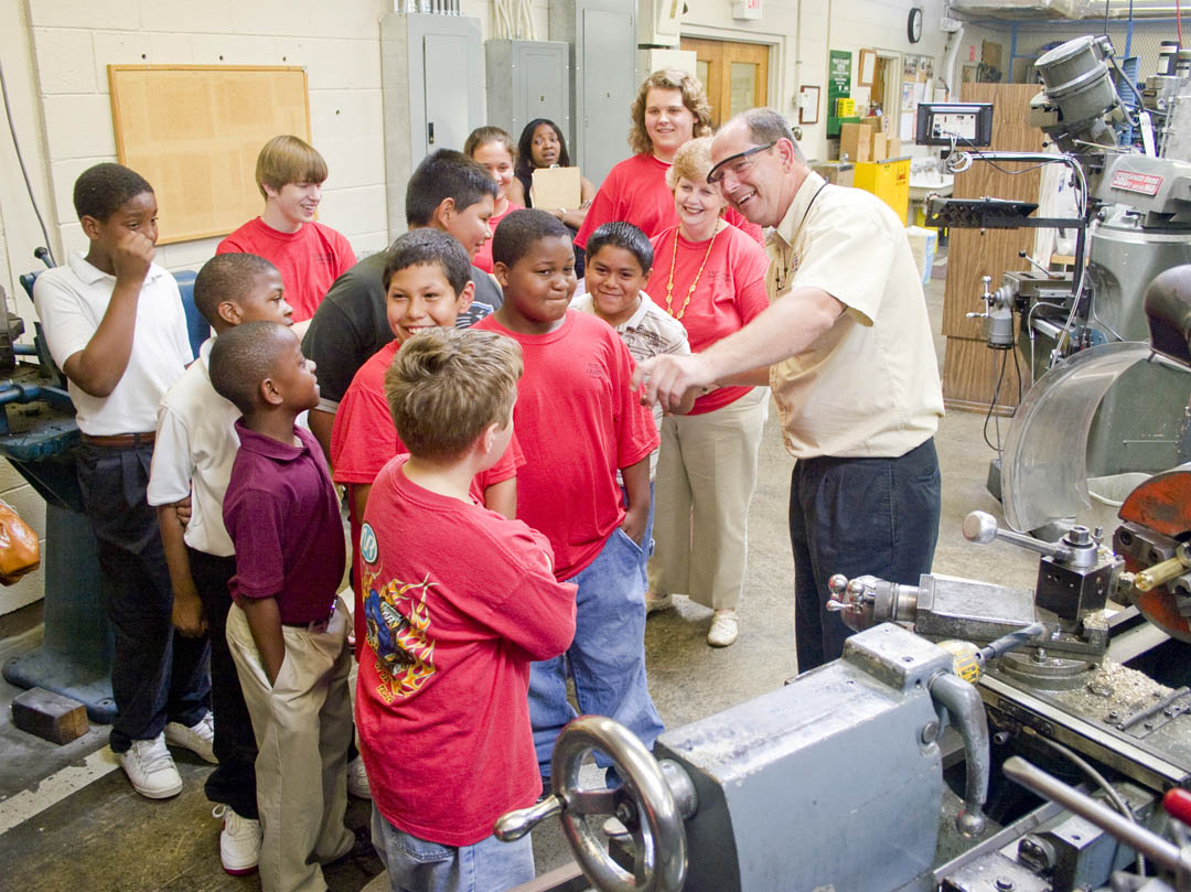 Click to enlarge,  Glenn Shearin (right), machining, tool and die instructor at Central Carolina Community College&#8217;s Lee County Campus, enjoys a laugh with visiting Lee County Schools students. The students are members of the school district&#8217;s Graduation Express, a program involving high school students, called Graduation Ambassadors, and elementary students, known as Future Graduates. The high school students mentor the younger ones to encourage them to complete high school and look forward to higher education. The students visited the college on May 27 to learn about some of the programs it offers and possible careers in those fields. Shearin spoke to the students about machining technology. The students also visited and learned about industrial systems, electronics engineering, and radio &amp;amp; television broadcasting programs as pathways to possible future careers.&amp;nbsp; 