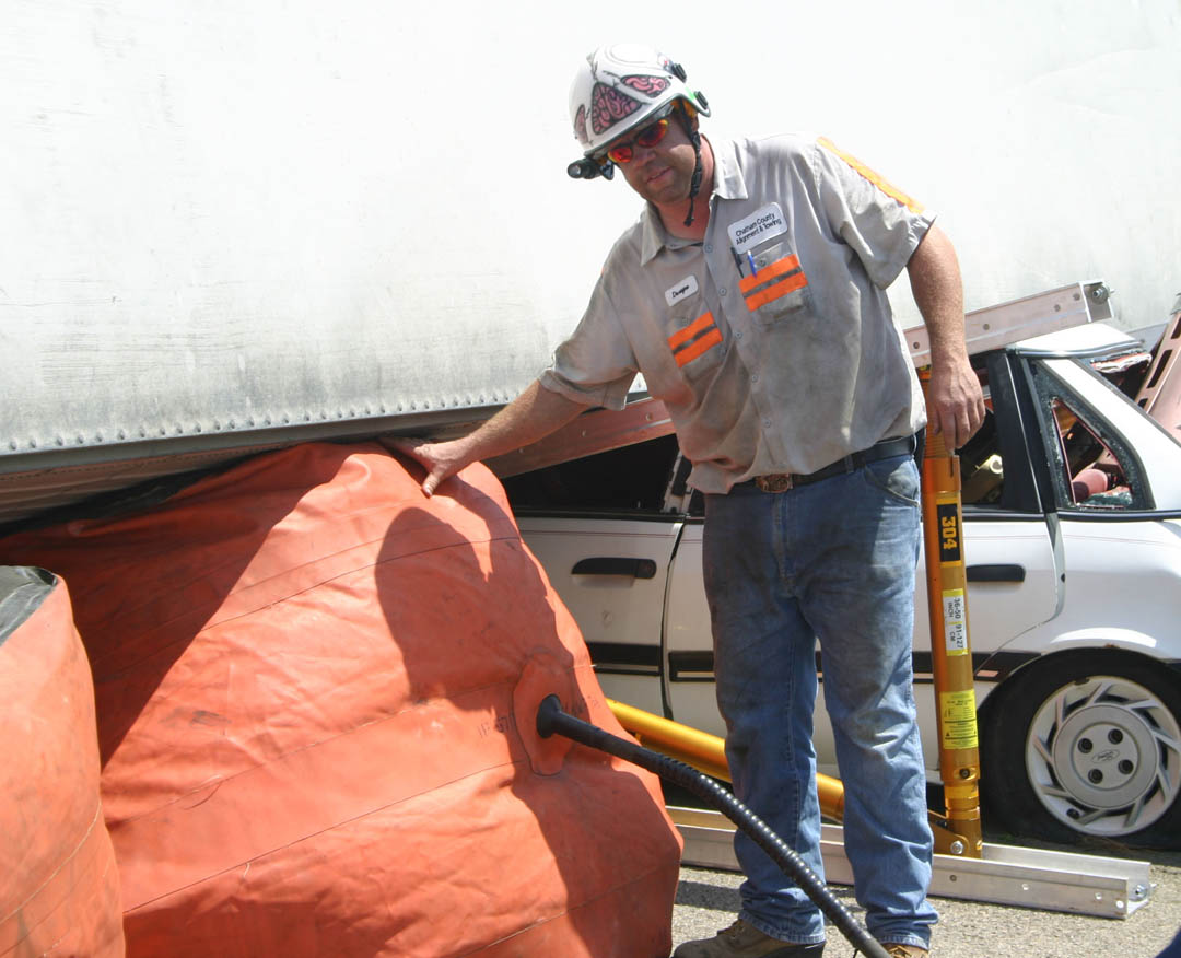 Click to enlarge,  Dwayne Smith, recovery operator for Chatham County Alignment &amp;amp; Towing, checks the inflation on airbags that are raising a tractor-trailer overturned on a car during the &#8216;Big Lift U&#8217; heavy load lifting training event June 13-14 at Central Carolina Community College&#8217;s Emergency Services Training Center in Sanford. Smith was one of the instructors for the event, which featured eight accident scenarios. Seventy-seven firefighters from eight states and Germany learned how to safely and effectively respond in accidents involving smaller vehicles with large, heavy vehicles, such as tractor-trailers, buses, concrete trucks, and a train. For more information on ESTC emergency training programs, call (919) 776-5601. 