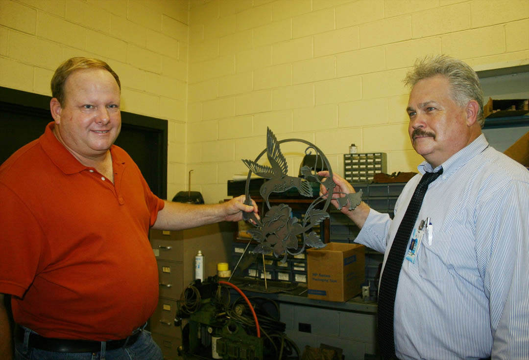 Click to enlarge,  Richard Clay Ingram (left), of Sanford, has established the Richard Clay Ingram Scholarship Endowment with the Central Carolina Community College Foundation to benefit Industrial Systems Technology students. The scholarship will pay all expenses for a student for a semester. Ingram, whose family owned the Sanford Coca Cola Bottling Company from 1907 to 2009, earned a welding certificate at the college in the 1970s. Following the meeting to set up the endowment, he was given a tour of the IST facilities in Joyner Hall at the college&#8217;s Lee County Campus. Allen Howington (right), IST chairman, shows Ingram a hummingbird-and-flower decoration created on the plasma-controlled cutter in the college&#8217;s welding shop. For information about the CCCC Foundation and opportunities to support education at Central Carolina Community College, call Diane Glover at (919) 718-7231, or e-mail at  dglover@cccc.edu . 