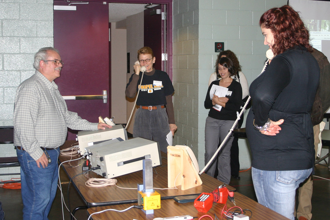 Click to enlarge,  Perry Emmons (left), Central Carolina Community College telecommunications instructor, enjoys the reaction of Linda Carmichael (center), career development coordinator at Chapel Hill High School, and Victoria Dietrich (right), Lee County High School counselor, as they and other counselors and career coordinators see the analog signals created by the phones they are using displayed on the equipment in front of Emmons. The demonstration was part of a Networking and Telecommunications Technology workshop, one of four programs featured at the college&#8217;s 34th annual Information and Planning Conference Nov. 13 at the Dennis A. Wicker Civic Center. Educators from schools in seven counties gathered to learn about educational opportunities for their students and graduates at the college. The 2009 event had workshops on the University Transfer/Associate in Science, Networking and Telecommunications Technology, Green Central Sustainable, and Business Technologies programs.&amp;nbsp; 