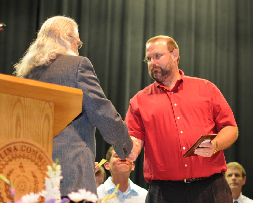 Click to enlarge,  Central Carolina Community College student Richard Bogart (right) of Chatham County, is congratulated by Jerry Clendenen, Electronics Engineering Technology lead instructor during the college&#8217;s May 5 Academic Excellence Awards program in the Dennis A. Wicker Civic Center. Bogart received the Academic Excellence in Electronics Engineering Technology Award and was selected for inclusion by Who&#8217;s Who Among Students in America&#8217;s Junior Colleges. Bogart received his Associate in Applied Science in Electronics Engineering Technology at the college&#8217;s May 13 commencement.  