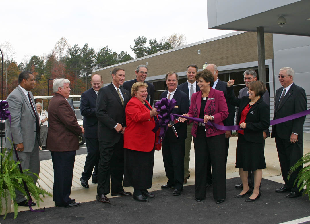 Click to enlarge,  Education, government and community leaders and members gathered Monday, Nov. 15, for the ribbon cutting/open house for Central Carolina Community College&#8217;s new Siler City Center in the Central Carolina Business Campus industrial park, in Siler City. Cutting the ribbon are (front, from left) Chatham Commissioner and CCCC Trustee Carl Thompson, CCCC Board of Trustees Chairman Ed Garrison, Siler City Mayor Charles Johnson, Chatham Board of Commissioners Chair Sally Kost, CCCC President Bud Marchant (wielding the scissors), CCCC Chatham Basic Skills Coordinator Sara Lambert, and CCCC Chatham Provost Karen Allen; and (back, from left) N.C. Sen. Bob Atwater, Chatham Commissioner Tom Vanderbeck, building architect Taylor Hobbs, Chatham Commissioner George Lucier, N.C. Speaker of the House Joe Hackney and Chatham Commissioner Mike Cross. The two-story, 23,800 square-foot Center will provide basic skills, adult education, workforce training, curriculum, and enrichment classes. 
