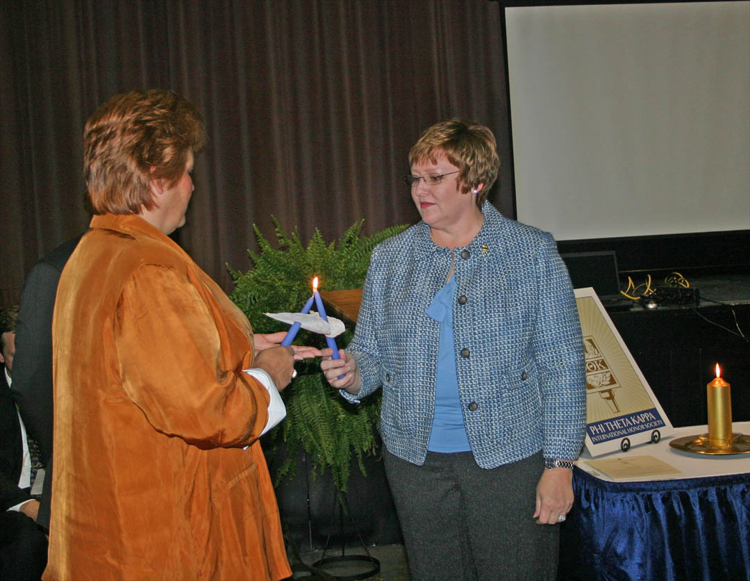 Click to enlarge,  Cheryl Reynolds (right), of Cameron, the first president of Central Carolina Community College&#8217;s new Beta Sigma Phi Chapter of Phi Theta Kappa International Honor Society, lights the candle of Dana Stone, of Dunn, the chapter&#8217;s vice president, during the Nov. 4 PTK chapter chartering and member induction ceremony at the Dennis A. Wicker Civic Center. PTK is the largest honor society in American higher education. To be eligible, students must have a minimum of 12 hours of associate degree course work and a grade point average of 3.5 or higher. The CCCC chapter requires a 3.7 GPA. Fifty-five CCCC students are charter members. 