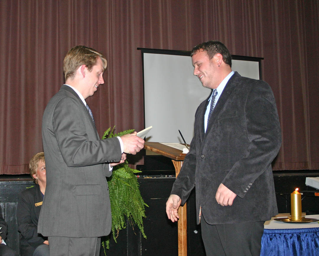 Click to enlarge,  Central Carolina Community College student Nicholas Wicker (right), of Mamers, receives his Phi Theta Kappa International Honor Society charter membership certificate from Mark Hall, the college chapter&#8217;s faculty advisor, during a Nov. 4 chartering and induction ceremony at the Dennis A. Wicker Civic Center. The college now has the Beta Sigma Phi Chapter of PTK, the largest honor society in American higher education. To be eligible, students must have a minimum of 12 credit hours and a grade point average of 3.5 or higher. The CCCC chapter requires a 3.7 GPA. Fifty-five CCCC students were inducted as charter members. 