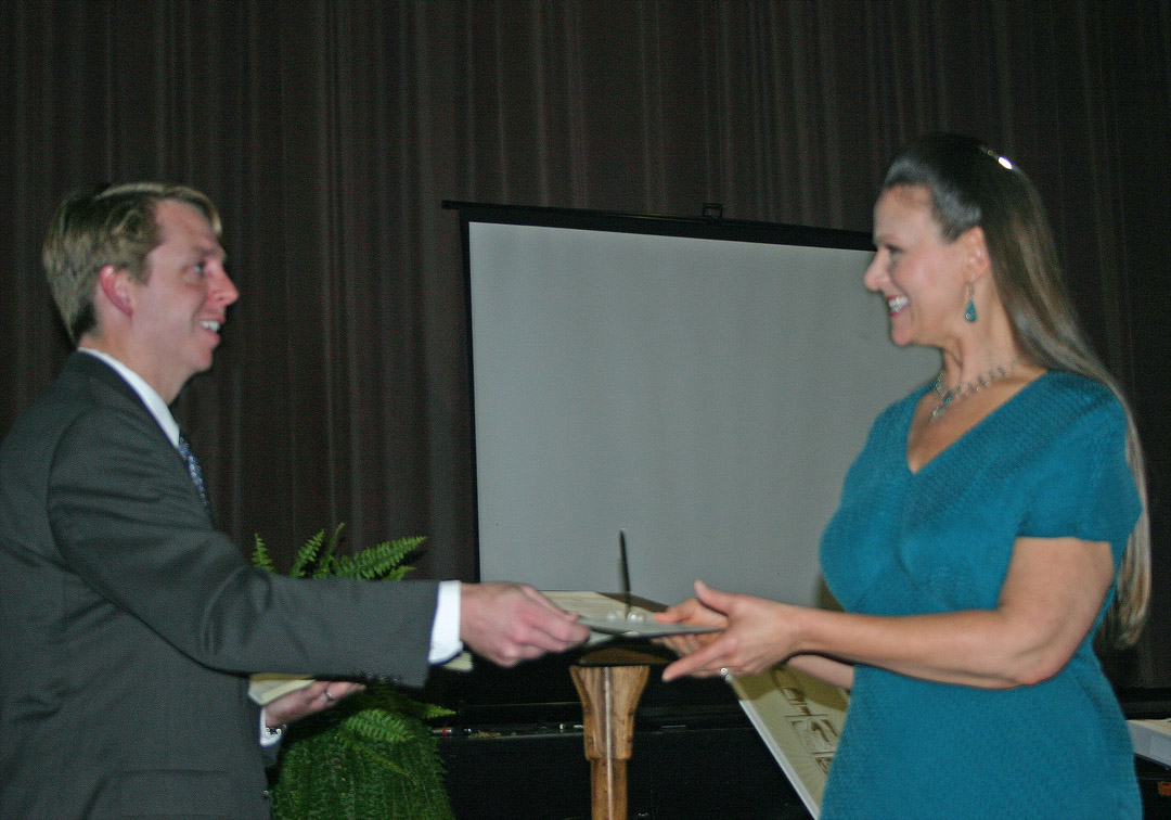 Click to enlarge,  Central Carolina Community College student Deborah Motter (right), of Sanford, receives her Phi Theta Kappa charter membership certificate from Mark Hall, the college chapter&#8217;s faculty advisor, during a Nov. 4 chartering and induction ceremony for the honor society. The college now has the Beta Sigma Phi Chapter of PTK, the largest honor society in American higher education. To be eligible, students must have a minimum of 12 credit hours and a grade point average of 3.5 or higher. The CCCC chapter requires a 3.7 GPA. Fifty-five CCCC students were inducted as charter members at the ceremony at the Dennis A. Wicker Civic Center. 