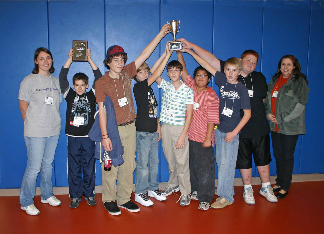 Click to enlarge,  The SanLee Middle School Stallionss team took home the Championship Cup and the Best Overall plaque from the Central Carolina Community College Robotics Competition, held Nov. 20 at the college&#8217;s Lee County Campus. Pictured (from left) are team coach and SanLee science teacher Shannon Willaert; team members Jonah Elliott, Cameron Marks, Brandon Donathan, Stephen Cameron, Angel Reyes, Cameron Lane, Joseph Knight; and assistant coach Sarah Reed. Team members not pictured are David Perdrisat, Anthony Thompson and Devin Rudisill. The competition, co-sponsored by CCCC, Communities in Schools, and Lee County Schools, was a scrimmage in preparation for the FIRST Lego League Tournament and was conducted by FLL rules. West Lee and SanLee, in Sanford, and two teams from Anne Chestnutt Middle School, in Fayetteville, competed in the scrimmage and will compete in the official 2010 FLL Tournament. The scrimmage and tournament require teams of students to do a presentation on a biomedical problem and then build and program a Lego robot to perform various biomedical tasks, such as inserting a &#8216;stent&#8217; in an &#8216;artery&#8217; made of Legos. 