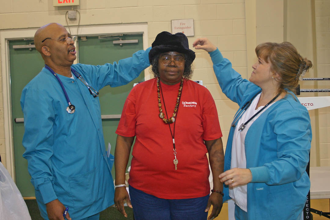 Click to enlarge,  Central Carolina Community College medical assisting students John Alston (left), of Pittsboro, and Jill Olive, of Mamers, measure Sanford resident Glenda Alston&#8217;s height during the Nov. 18 Living Well Health Fair at the Stevens Center, in Sanford. The students volunteer at the fair as part of their community outreach efforts. Fifteen health, medical, and medical education organizations, including the college&#8217;s medical assisting and dental hygiene programs, offered visitors the opportunity to have their blood pressure, vision, cholesterol, height, weight, flexibility and other health indicators checked as well as receive information about staying healthy. 