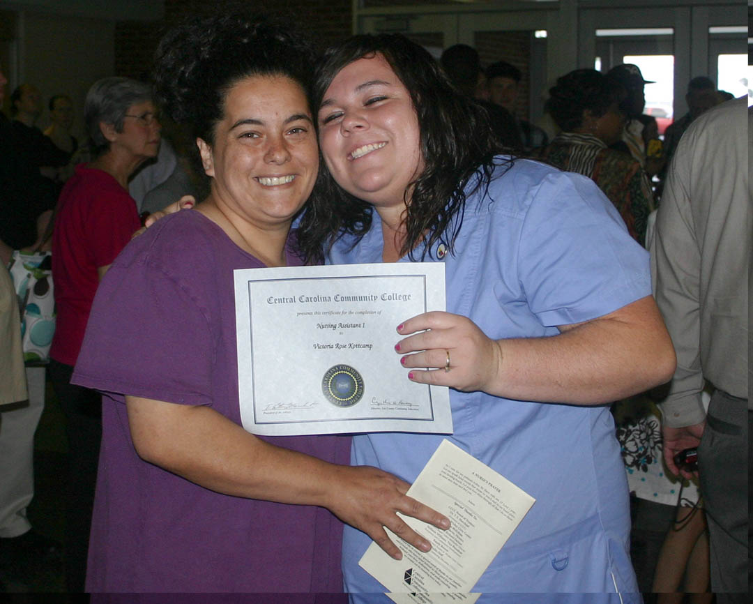Click to enlarge,  Victoria Kottcamp (right), of Lee County, gets a congratulatory hug from her mother, Etta Kottcamp, after receiving her Nursing Assistant I certificate during the May 18 Medical Programs Graduation for Central Carolina Community College&#8217;s Continuing Education Department. More than 100 students earned certificates in various medical programs, with some earning more than one. About 50 attended the graduation ceremony. 