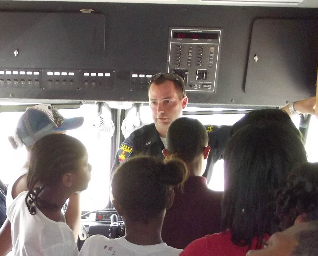 Click to enlarge,  Officer T.W. Herring of the Sanford Police Department explains the department&#8217;s mobile command unit to some students in Lee County Schools Graduation Express Program. The police department was one of several local agencies and businesses participating Tuesday in Central Carolina Community College&#8217;s Truck-Transportation Day at its Emergency Services Training Center. 