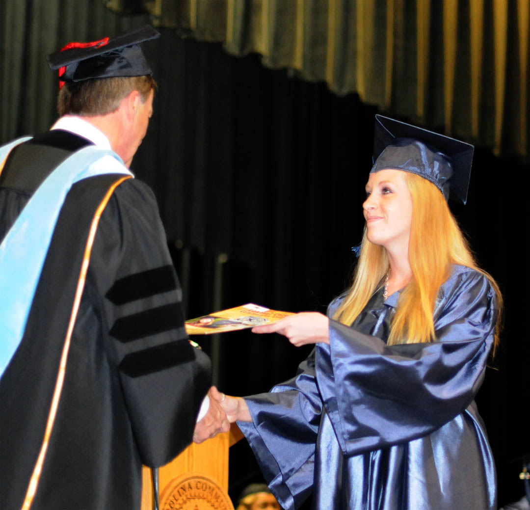 Click to enlarge,  Jennifer Howell, of Lee County, smiles as Central Carolina Community College President Bud Marchant congratulates her at the college&#8217;s Adult High School/GED graduation exercises June 16. Howell was one of 143 students who completed their high school studies during the spring semester. Howell was one of three graduating student speakers at the commencement and also received the Donald N. Buie Memorial Scholarship to continue her studies at the college. 