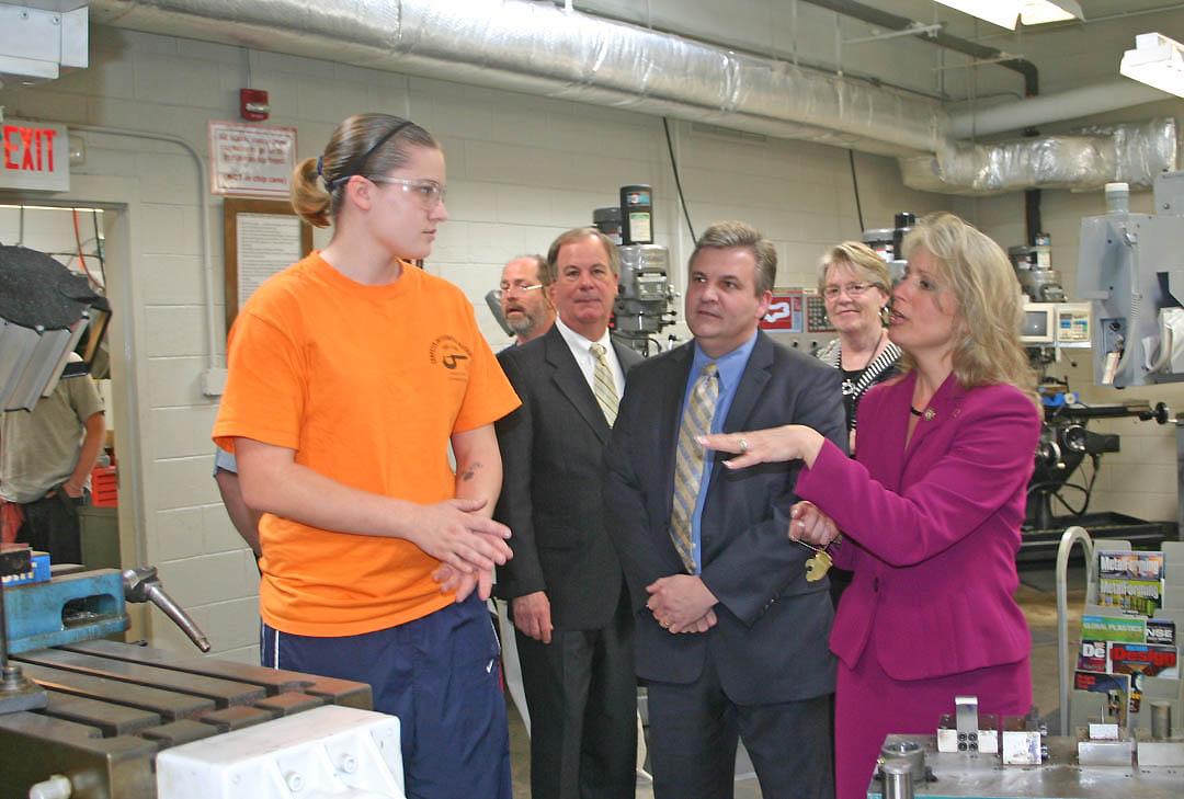 Click to enlarge,  U.S. Rep. Renee Ellmers (right) asks Central Carolina Community College Computer Integrated Machining student Diamond Bartlett (left) about what she is learning during a March 14 visit to the program at the college's Lee County Campus. N.C. Rep. Michael Stone (third from right), and Lee County Board of Commissioners Chairwoman Linda Shook (second from right) accompanied Ellmers. Hosting the visit were CCCC President Bud Marchant (second from right) and faculty from the program, including machining instructor Glenn Shearin (behind Marchant). The elected officials visited the campus to see one of the college's high technology workforce training programs that can help meet the state and nation's need for a highly skilled workforce. 