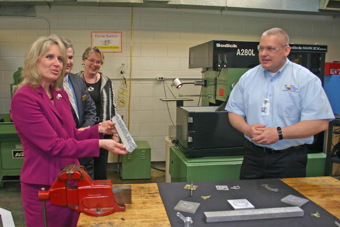 Click to enlarge,  U.S. Rep. Renee Ellmers (left) expresses her surprise and pleasure at being presented a desk nameplate created for her by Central Carolina Community College's Computer Integrated Machining program students using a computer-guided machine. Accompanying Ellmers on her visit were (behind Ellmers) N.C. Rep Michael Stone and Lee County Commissioner Linda Shook. Chris Jackson (right), Machining instructor, made the presentation. The elected officials visited the campus to see one of the college's high technology workforce training programs that can help meet the state and nation's need for a highly skilled workforce. 