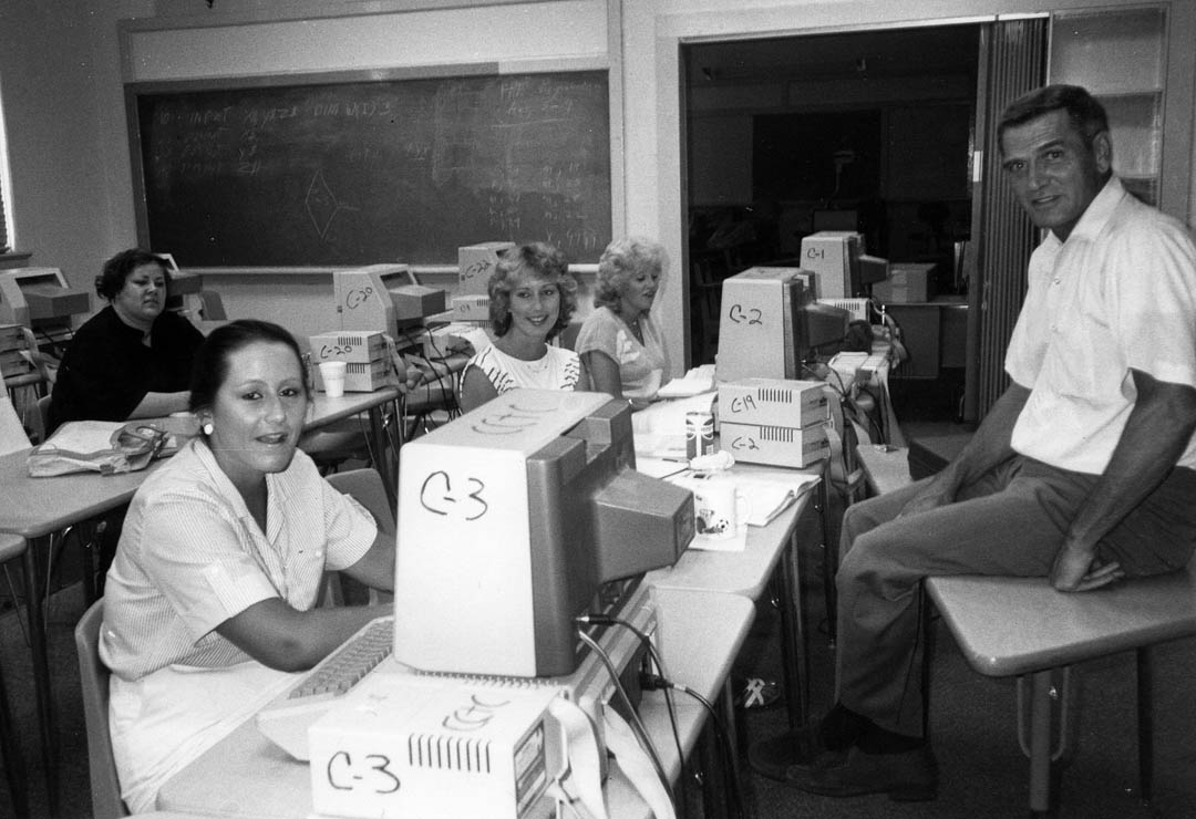 Click to enlarge,  Central Carolina Community College has been serving students in Chatham County since 1964. It occupied the old Henry Siler School building, in Siler City, from 1984 until the opening of the Siler City Center in 2010. In this summer 1985 photo at Henry Siler, computer class instructor Eddie Cheek (right), and students pause for a picture taking. Class member Theresa Wright (front left) was secretary to then-CCCC Chatham Coordinator Charles White. The college at that time was known as Central Carolina Technical College. CCCC is celebrating 50 years of service to its communities during the 2011-12 school year. The Chatham Celebration takes place at the Pittsboro Campus, 764 West St., Saturday, April 28. Everyone is invited to this event filled with activities for all the family. A 5K Rabbit Run starts at 8 a.m., with all-day free events running 9 a.m.-1:30 p.m. For more information about the celebration, go to  www.cccc.edu/50years/events . 