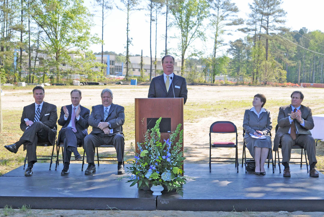 Click to enlarge,  Central Carolina Community College President Bud Marchant (at lectern) addresses the more than 100 people who attended the April 12 groundbreaking for the college's new Health Sciences Building in Brightwater Science and Technology Campus, in Lillington. Also speaking were (from left) Red Rock Developments CEO William Smith, Harnett Health Systems President/CEO Ken Bryan, Harnett County Board of Commissioners Chairman Tim McNeill, and CCCC Board of Trustees Chairman Julian Philpott (right). Faithe Beam (second from right), Campbell University campus minister, gave the invocation. The facility, which will open fall 2013, will provide state-of-the-art training in the health care field. 
