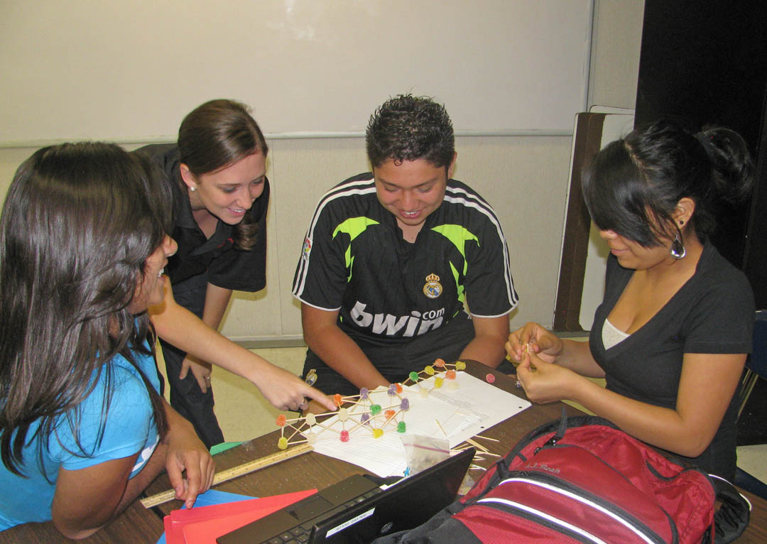 Click to enlarge,  Lee Early College students learned impressive lessons about the relevance of geometry to everyday life when teachers Jenna Rice and Whitney Coon had their classes build weight-bearing bridges using gumdrops and toothpicks. During the building, (from left) student Frida Rodriguez, geometry teacher Whitney Coon, and students Jerry Pineda and Dulce Galvez examine their bridge. The students discovered that congruent triangles are best for distributing weight and maintaining a bridge's strength and stability. 