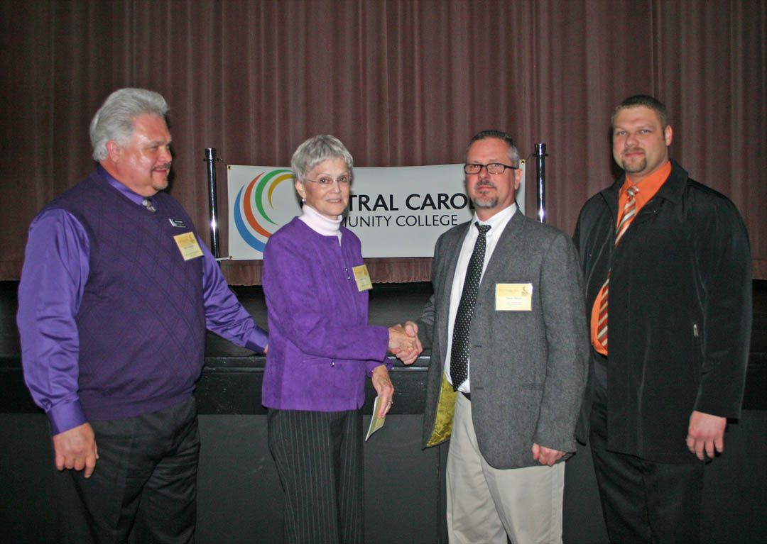 Click to enlarge,  Stevie Messer (center, right), of Harnett County, expresses his gratitude to Donald N. Buie's widow, Jeannie Buie (center, left) for the Donald N. Buie Memorial Scholarship he received from the Central Carolina Community College Foundation to help him attend school. Messer, whose job of 19 years disappeared in the recession, is now studying Industrial Systems Technology at the college. Also pictured are Allen Howington (left), chair of the IST Department, and Wesley Womack (right), IST instructor. The CCCC Foundation is a 501(c)(3) charitable organization affiliated with, but independent of, Central Carolina Community College. It receives donations of money and equipment on behalf of CCCC and uses them to promote the educational mission of the college and assist students through scholarships and grants. For information on establishing scholarships or endowments, contact CCCC Foundation Executive Director Diane Glover, 919-718-7231 or dglover@cccc.edu, or Associate Director Emily Hare, 919-718-7230 or ehare@cccc.edu. To apply for a scholarship, contact the CCCC Financial Aid Office at /www.cccc.edu/financialaid/ or 919-718-7229. 