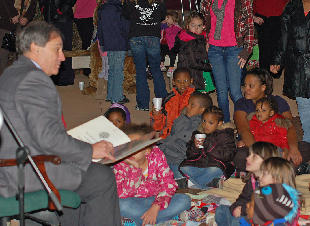 Click to enlarge,  Children listen with anticipation as Central Carolina Community College Board of Trustees Chair Julian Philpott (left) entertains with a reading of 'T'was the Night Before Christmas' at the college's Christmas Tree Lighting/Santa Visit Dec. 6 at the Lee County Campus. Children and families had their pictures taken with Santa Claus and Charlee Cougar, enjoyed music by members of the Southern Lee High School Marching Band, watched the tree lighting, enjoyed cookies and hot chocolate, and took home a wooden tree ornament.  