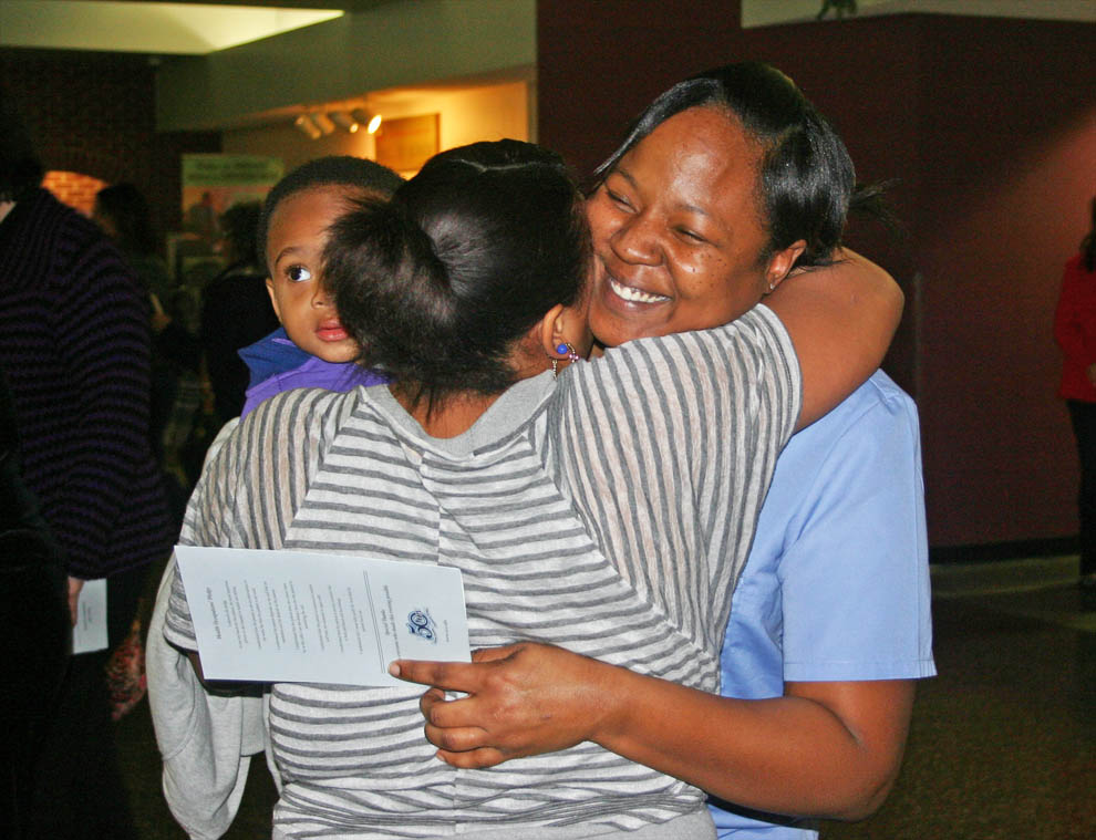 Click to enlarge,  Harnett graduates   Jasmine Thomas (right), of Lillington, gets a congratulatory hug from her sister, Dominique Trammell, following the Continuing Education Medical Programs graduation exercises Dec. 13 at Central Carolina Community College. Thomas received her Nurse Aide I certificate and plans to continue her education in the healthcare field. The graduation was the largest Con Ed Medical Programs graduation the college has ever had, with more than 200 students and approximately 1,100 friends and family filling the Dennis A. Wicker Civic Center's main hall.  