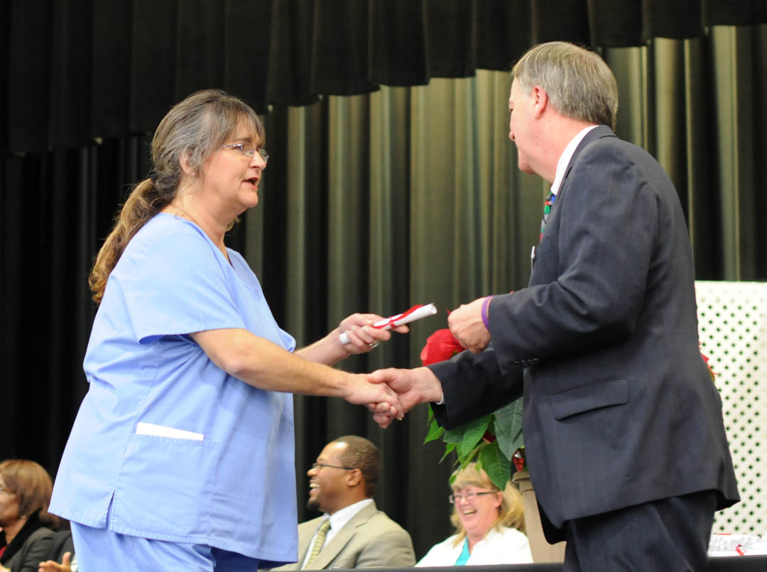Click to enlarge,  Kathryn Melvin (left), of Harnett County, receives her Nurse Aide I Certificate from Central Carolina Community College President Bud Marchant during the college's Continuing Education Medical Programs Graduation Dec. 13 at the Dennis A. Wicker Civic Center. Melvin was one the student speakers at the event. She told of the downward spiral she had experienced earlier in her life through drugs and alcohol and encouraged the graduating students to stay on the right path. The graduation was the largest Con Ed Medical Programs graduation the college has ever had, with more than 200 students and approximately 1,100 friends and family filling the Civic Center's main hall.  