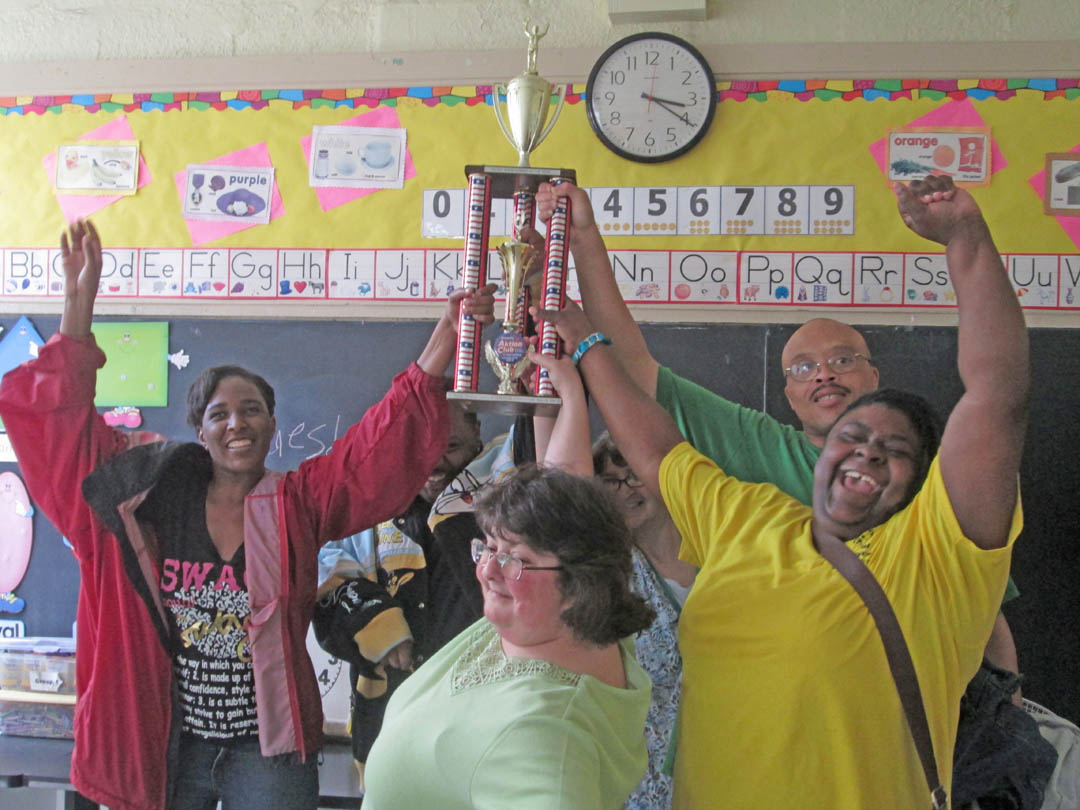 Click to enlarge,  Students in instructor Elizabeth King's Compensatory Education class at Central Carolina Community College's Lillington Adult Education Center show off the first-place trophy they won at the Kiwanis Aktion Club Convention in 2012 for their rendition of 'God Bless the USA.' Holding the trophy are (front, from center) Natalie Barnes and Patrice McClain, and (back, from left) Ronnell Williams, Jamal Cameron, Melissa Williams, and Chico Williams. For more information on CCCC's Compensatory Education program, contact King at 910-814-8977 or e-mail her at  .  