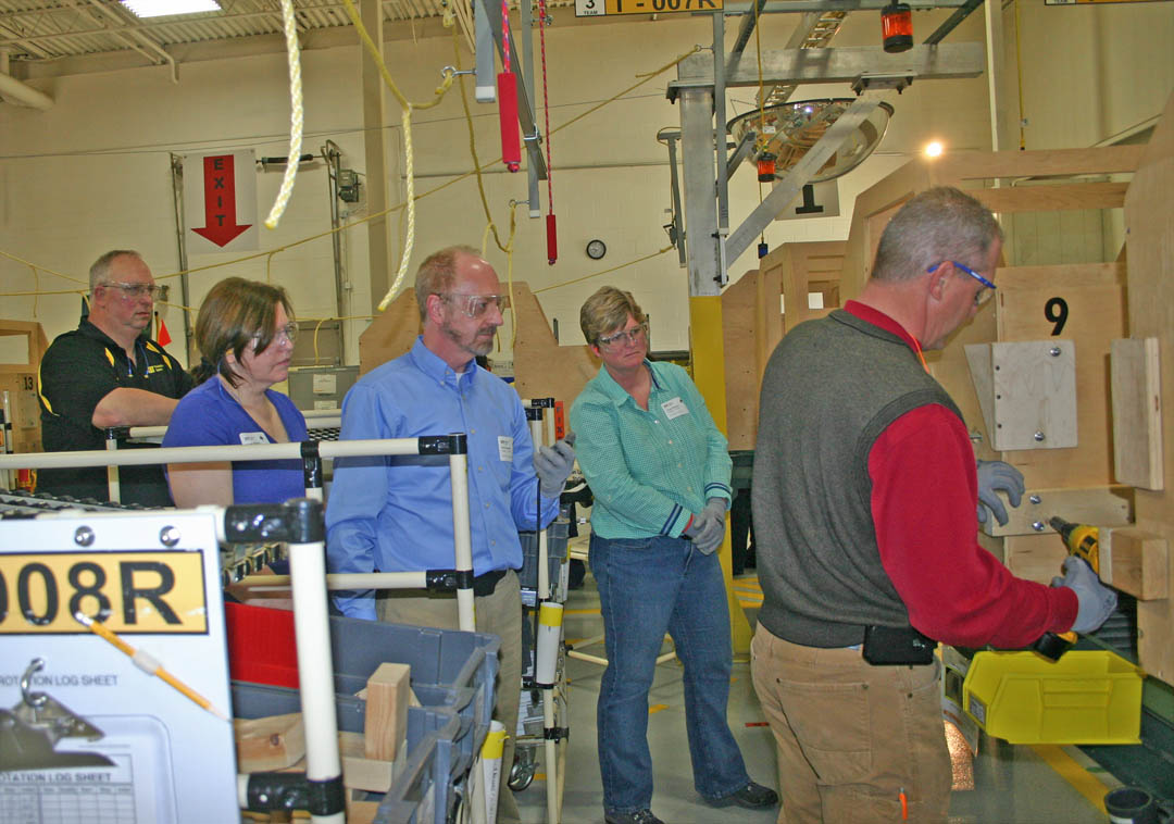 Click to enlarge,  Industry training directors and administrators from community colleges in eastern North Carolina have been coming to Central Carolina Community College's Industry Training Center at the Lee County Innovation Center to experience the simulated work environment (SWE) and other workforce training programs. They then share this information with industries they work with. Pictured (from left) certified SWE trainer Bob Jones, Dr. Doris Carver, vice president of Continuing Education at Piedmont C.C., Dr. Peter Wooldridge, interim vice president for Corporate and Continuing Education at Durham Technical C.C., and Laura Coffee, dean of Continuing Education at Rockingham C.C., observe as David Pritchett, coordinator for Business and Industry at Guilford Technical C.C.,  practices assembling a mock-up of a skid steer loader. SWE is one of many training programs provided by CCCC for local industry at the Innovation Center. For information on CCCC's industry training programs, visit www.edu/ecd/departments/businessindustry/ or call the Industry Services Office at 919-718-7212.  
