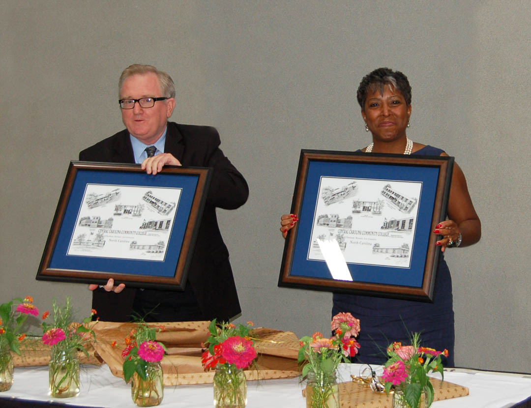 Click to enlarge,  Departing Central Carolina Community College Board of Trustees members R.V. Hight (left) and Ophelia Livingston, both of Lee County, were honored at a reception prior to the board's July 24 meeting in the Dennis A. Wicker Civic Center. Hight, editor of The Sanford Herald, had served as a trustee since 2005 and Livingston, owner of OWL Risk Management, since 2009. Both show off the Jerry Miller prints of CCCC buildings they received. Departing trustee Douglas Wilkinson Jr., also of Lee County, president of Wilkinson Cadillac Pontiac GMC, was unable to attend the reception. He was first appointed by Gov. Mike Easley in 2005 and reappointed by Gov. Bev Perdue in 2009. Also completing their terms on the board were Tracy Hanner and George Lucier, of Chatham County, and Tim McNeill, of Harnett County. They will be honored at future board meetings in their counties. For more information about CCCC and its programs, visit www.cccc.edu. 