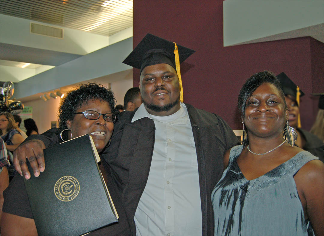 Click to enlarge,  Carlton Fortune (center) of Lee County, gets congratulatory hugs from his mother, Joyce Fortune (left) and sister, Jennifer Fortune, at his Aug. 6 graduation from Central Carolina Community College. Fortune received his Associate in Arts, Diploma and Certificate in Automotive Systems Technology. The graduates earned more than 400 degrees, diplomas and certificates, with some students earning more than one. Some will continue their education at four-year institutions, while most will take their new skills and knowledge directly into the workplace. For information about programs at CCCC, visit www.cccc.edu/. 