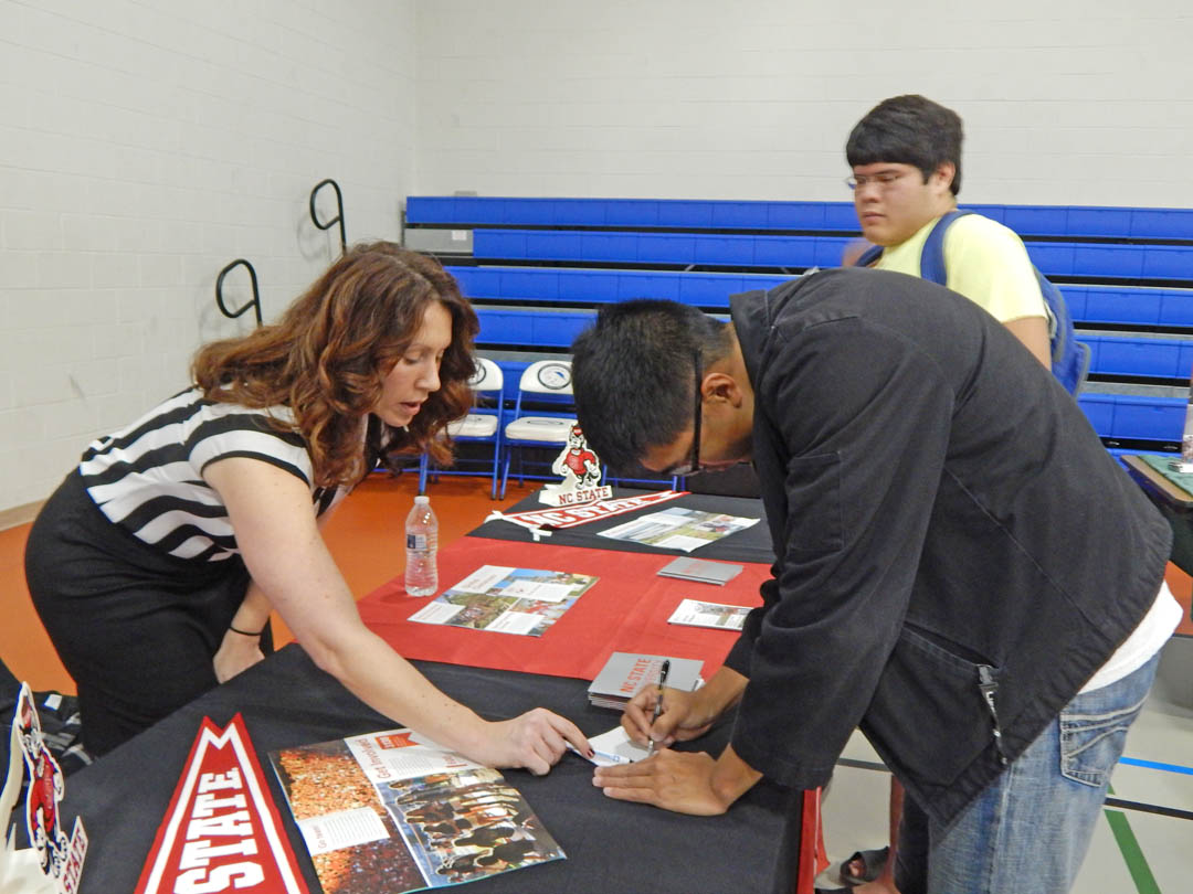 Click to enlarge,  Dana Troutman (left), assistant director of N.C. State University's Office of Undergraduate Admissions, speaks with Central Carolina Community College student Jerry Khamdy, of Cary, while student Scott Lewis (back), of Sanford, listens during the college's Dec. 6 University Transfer Day. The event, held in the Lee County Campus gym, attracted representatives from 20 four-year colleges and universities. All were eager to tell the approximately 200 students who attended what their schools offer, what they look for in applicants, how to apply, and to answer any questions the students had. For more information about university transfer programs at CCCC, visit www.cccc.edu/admissions/audience/transfer/. 