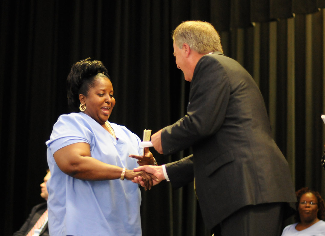 Click to enlarge,  Mary Battle (left), of Lee County, is congratulated by Central Carolina Community College President Bud Marchant on receiving her Nurse Aide I certificate at Central Carolina Community College's May 29 Continuing Education Medical Programs Graduation in the Dennis A. Wicker Civic Center. More than 300 completed their studies during the spring semester in the fields of Nurse Aide I and II, EKG Technician, Phlebotomy Technician, Pharmacy Technician, Central Sterile Processing Technician and Sleep Disorder Technician. Approximately 200 took part in the graduation ceremony. For more information about Continuing Education medical programs, call Lennie Stephenson, 910-814-8833 or email lstephenson@cccc.edu in Harnett County; Heike Johnson, 910-545-8682 or hjohnson@cccc.edu in Chatham County; or Joy McPhail, 919-777-7787 or jmcphail@cccc.edu in Lee County. 