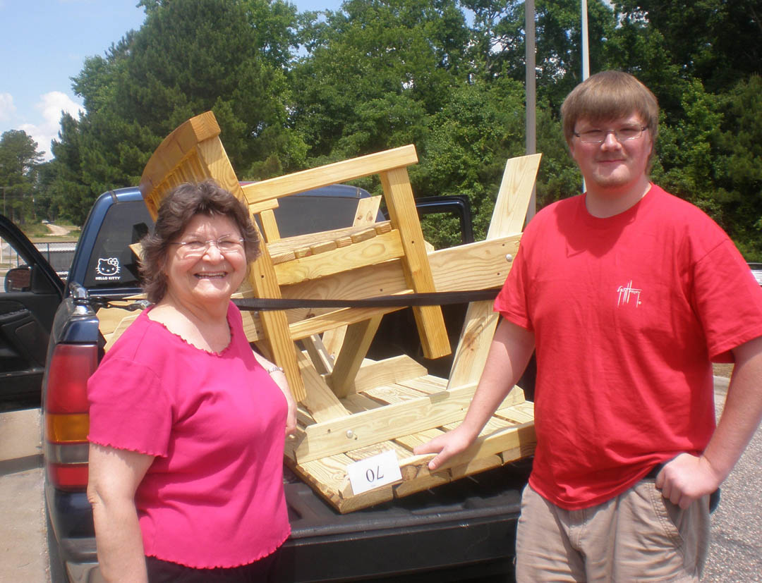 Click to enlarge,  Barbara Lloyd (left), of Lillington, and  grandson John Stephenson, of Smithfield, load up their purchases at the Central Carolina Community College Foundation's June 7 Furniture Auction at the college's Harnett County Campus. The purchases included a porch bench, picnic table and two jewelry boxes. Proceeds from the auction help provide financial aid for Harnett County students through an endowed scholarship fund managed by the CCCC Foundation. The proceeds also pay for materials used to produce the auction items. For more information about the CCCC Foundation Furniture Auction, contact CCCC's Harnett Provost Bill Tyson at 910-893-9101 or btyson@cccc.edu. Go online to www.cccc.edu/foundation/events/furnitureauction to see a photo gallery of the auction pieces. 