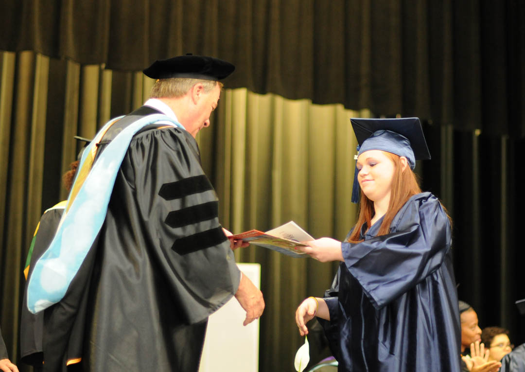 Click to enlarge,  Graduating student Deandra Bennett, of Harnett County, receives congratulations from Central Carolina Community College President Bud Marchant, during the college's June 19 Adult High School/GED graduation at the Dennis A. Wicker Civic Center. Seventy students completed their studies for a diploma during the spring semester. Most plan to continue their education at the college. The Adult High School and GED programs are under the college's College and Career Readiness Department. For more information, visit www.cccc.edu or call a CCR office: Chatham County - 919-545-8661 at the Siler City Center or 919-545-8028 at the campus in Pittsboro; Harnett County - 910-814-8974; or Lee County - 919-777-7707 at the Lifelong Learning Center at W.B. Wicker Business Campus. Para mas informacion en espanol - 919-545-8667 or jherbon@cccc.edu. 