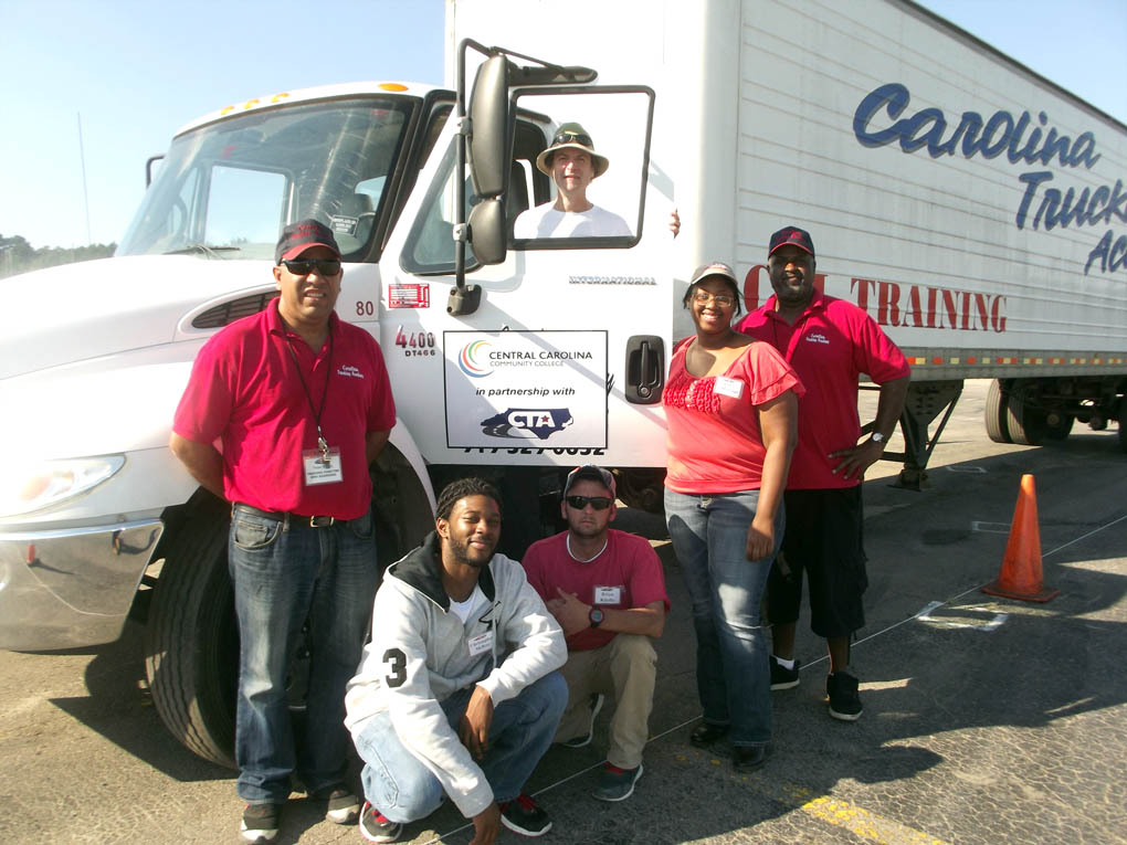 Click to enlarge,  Members of the current Commercial Driver's License (CDL) class being offered through Central Carolina Community College are pictured with two of their instructors. Pictured are, left to right: Instructor Victor Torres, Christopher McKoy, Brian Kindle, Russell Moore (in window), Ashley Yarborough and Instructor Joe Henderson. 