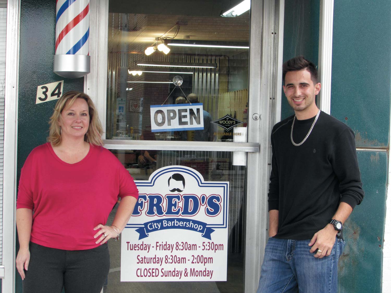 Click to enlarge,  Angela Butler and employee Daniel Sweatt stand outside the door of Fred's City Barber Shop in Hamlet. 