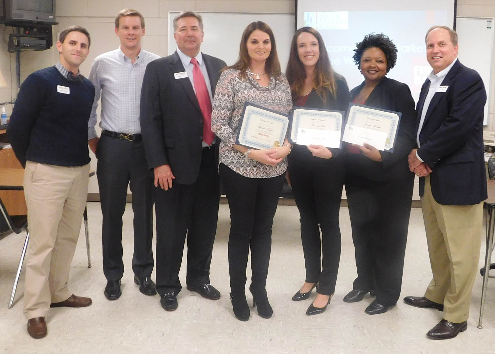 Click to enlarge,  First Bank presented a scholarship award to the winning Central Carolina Community College team that participated in the Stock Market Game. Pictured are (left to right) Travis Bailey, Hunter Young, and Allen Smith of First Bank; students Shannon Eason, Amanda Holt, and Jennifer Womble; and Stewart Forbes of First Bank. 