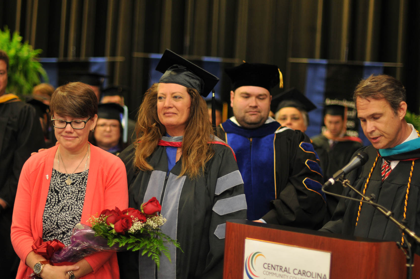 Click to enlarge,  Ken Hoyle Jr. (right), Vice President of Student Services, memorialized former Veterinary Medical Technology staff member Jonathan Loftis by recognizing his wife, Kelley (left), at the Central Carolina Community College graduation on May 12. "Kelley, we all miss Jonathan and the College has fully shared in your loss," said Hoyle. "Please know that as each new student is admitted to the Vet Med program, as each graduate receives their diploma, and as each animal is then touched and healed by these graduates, Jonathan's legacy will go on and on." Jonathan Loftis served as Animal Facilities Manager and Instructor in the CCCC Veterinary Medical Technology program. Pictured next to Kelley Loftis is CCCC VMT Chair Kim Browning. 