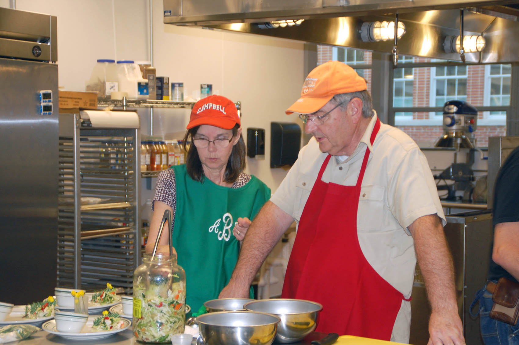 Click to enlarge,  Jim and Ann Burgin of Angier, shown here, were students in a BBQ Essentials class at Central Carolina Community College and won a cook-off that ended the class. They are shown here preparing marinated slaw that was part of their presentation. 