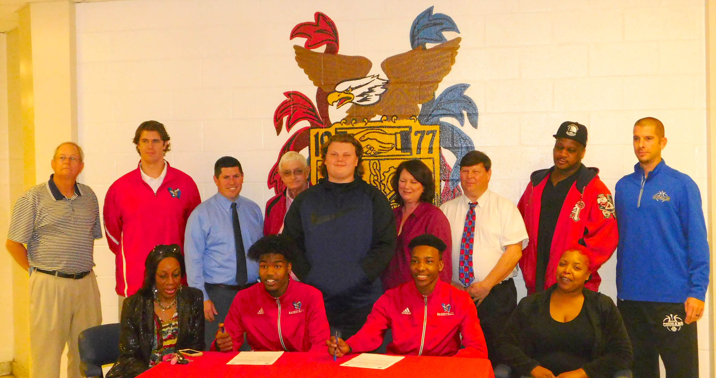Click to enlarge,  Darnell Carver and Jamar Butler (seated, center), of Western Harnett High School, signs with the Central Carolina Community College men's basketball program. 
