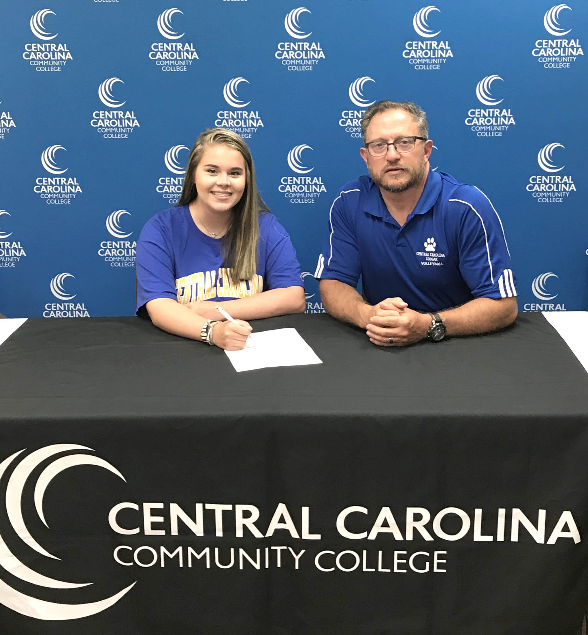 Click to enlarge,  Paige Weaver (left) signs with the Central Carolina Community College volleyball program. She is seated beside CCCC Volleyball Coach Bill Carter. For more information about Central Carolina Community College and its programs, visit its website, www.cccc.edu or call the college at 919-775-5401. 