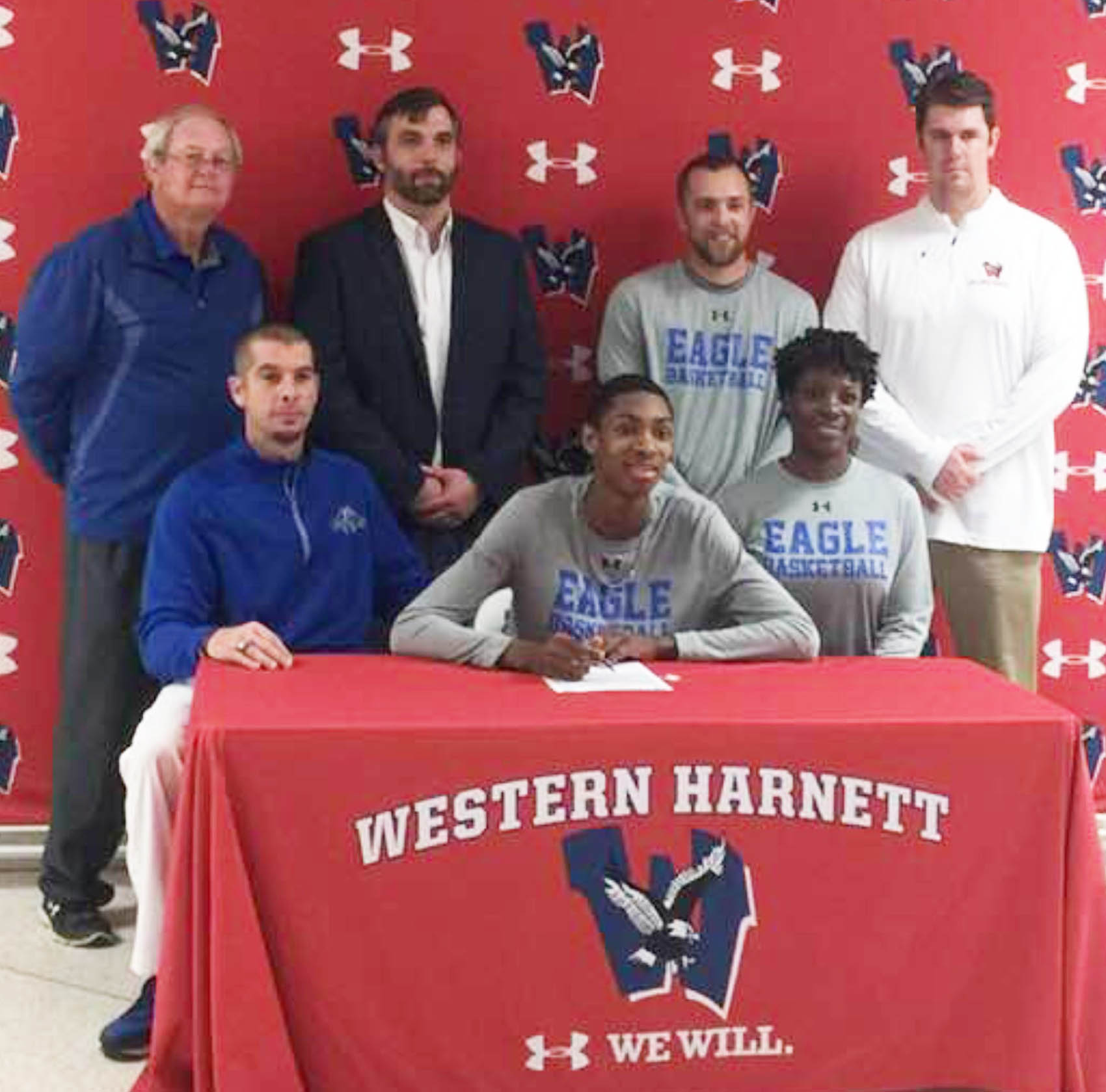 Click to enlarge,  Tobias Dillard (seated, center), of Western Harnett High School, signs with the Central Carolina Community College men's basketball program. 