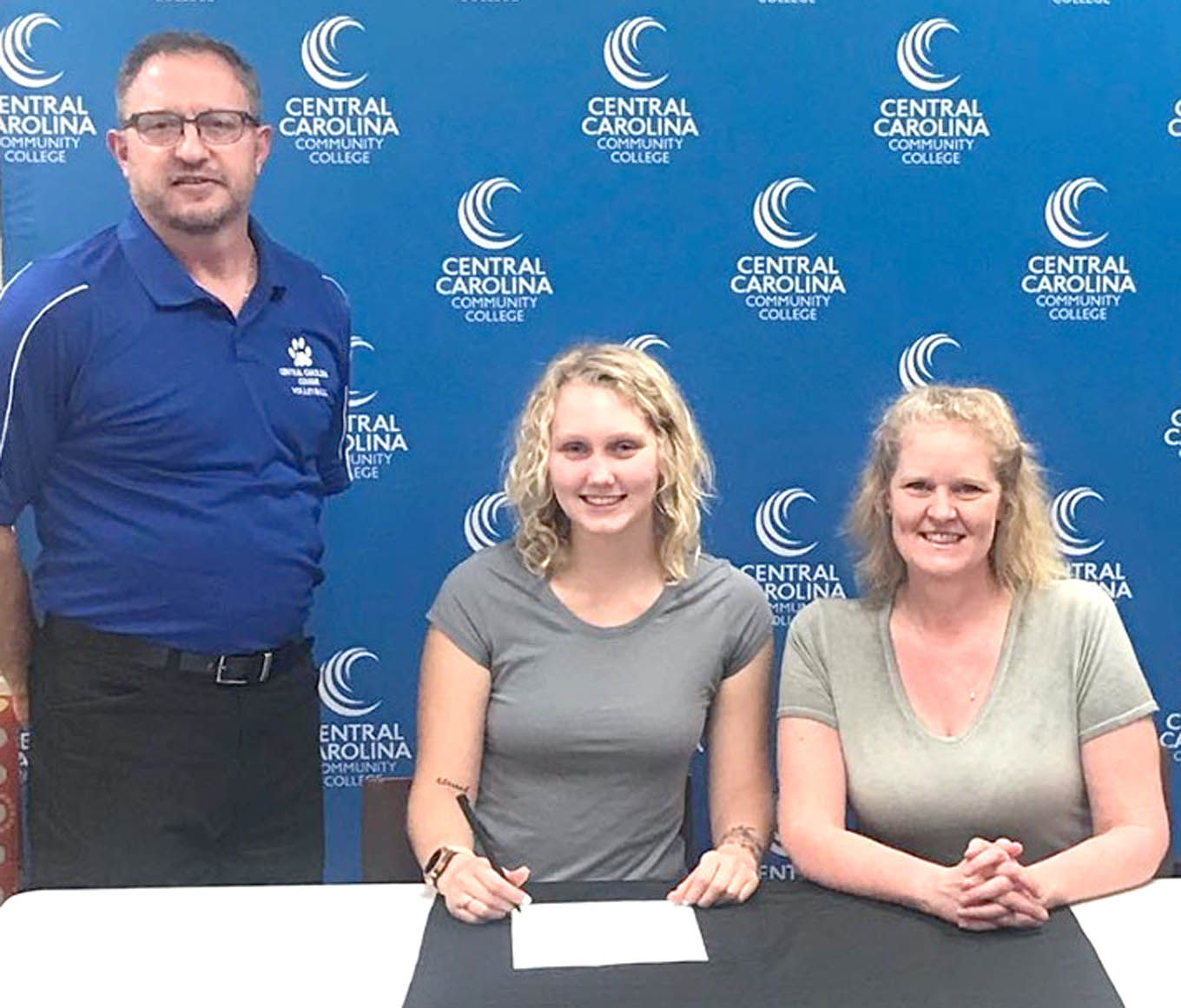 Click to enlarge,  Alexis Rolka (seated left), who attended Northwood High School in Chatham County, will join the CCCC volleyball program. Seated at right is her mother, Paula Rolka. Standing at left is CCCC Volleyball Coach Bill Carter. 