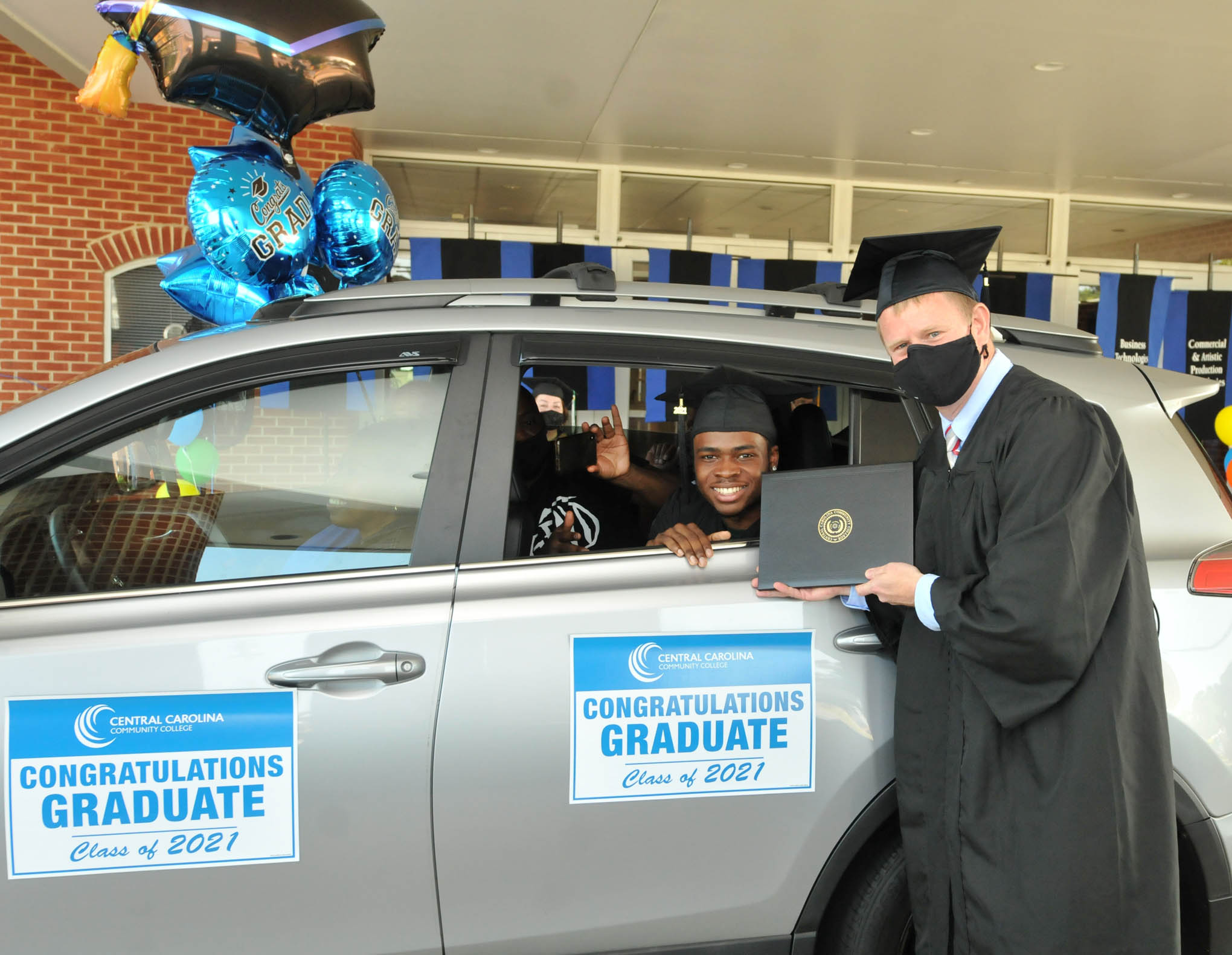 Click to enlarge,  Central Carolina Community College Executive Vice President / Chief Financial Officer Dr. Phillip Price visits with one of the new CCCC graduates. Each student was given a vehicle magnet signifying his/her graduation from the college. 