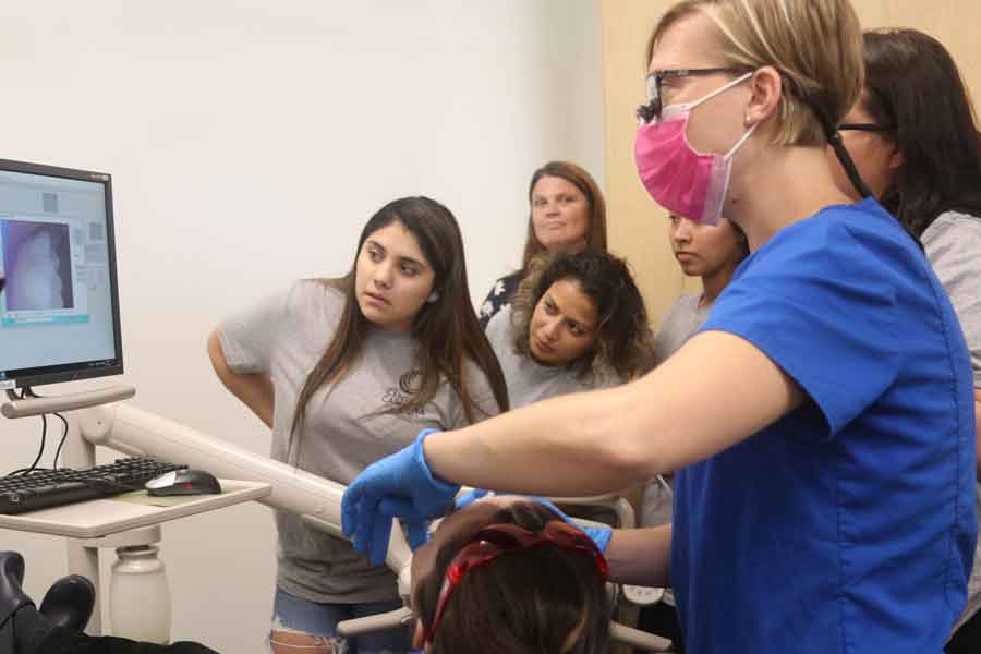 Click to enlarge,  Students in this summer's Prep for Success Academy examine a tooth being photographed by instructor Danielle Bruner during her hour-long intraoral photography demonstration. The four-day academy is a mix of dental education, academic counseling and college recruiting for students who are seriously considering the competitive dental programs at Central Carolina Community College. 